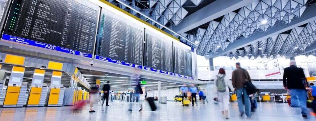 Stopover: Aeroporto internacional com telão com chegadas e partidas com pessoas caminhando rapidamente pelo saguão
