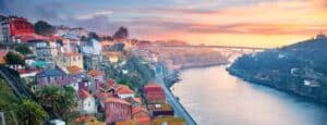 Vinícolas do Porto: Vista aérea do Rio Douro com casas e caves nos morros com o pôr do sol no horizonte