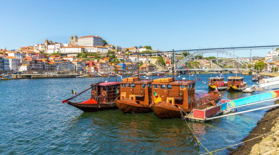 Barcos ancorados no Rio Douro aguardando os turistas para fazer o passeio pelo rio. Ao fundo a cidade do Porto e a ponte D. Luís