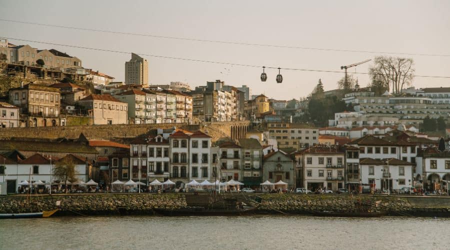 Vila Nova de Gaia, com o Teleférico, restaurantes e caves ao fundo, e o Rio Douro margeando a região