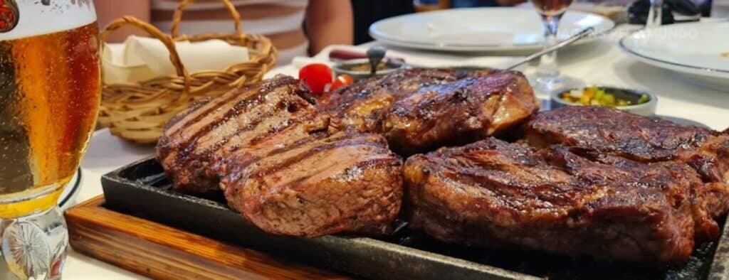 Os melhores restaurante em Buenos Aires: Carnes em uma chapa de ferro em cima da mesa e uma cerveja gelada ao lado