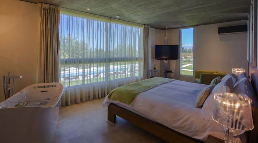 Entre Cielos Mendoza: quarto Moderno com Banheira, um design moderno com uma cama grande e uma banheira elegante próxima à janela, oferecendo relaxamento com uma vista dos vinhedos