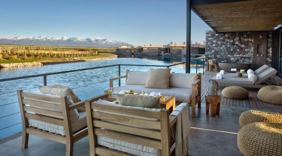 The Vines Resort Mendoza: varanda com Vista para o vinhedo: Exibe uma área de estar externa luxuosa em uma varanda, com sofás confortáveis e uma vista panorâmica das videiras e montanhas ao fundo.