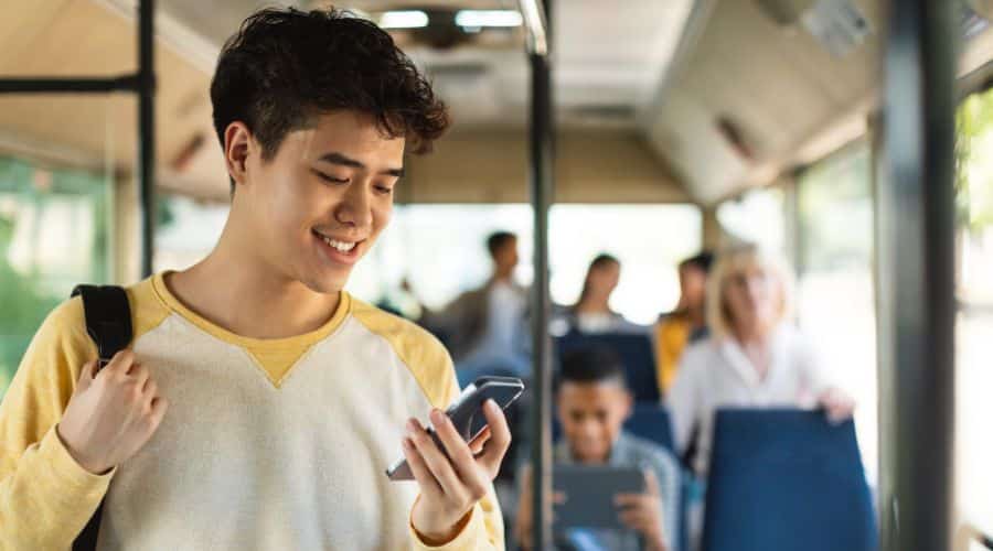 Chip de internet para Orlando: Menino com camiseta branca com o celular na mão dentro do ônibus público usando o Maps para chegar no destino.