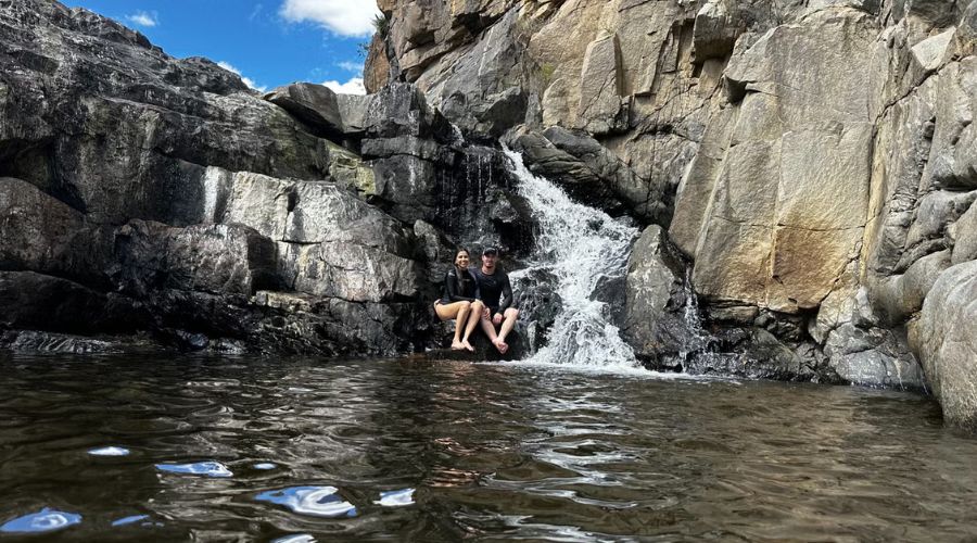 Passeios pela caatinga paraibana: Casal sentado na cachoeira que está no roteiro