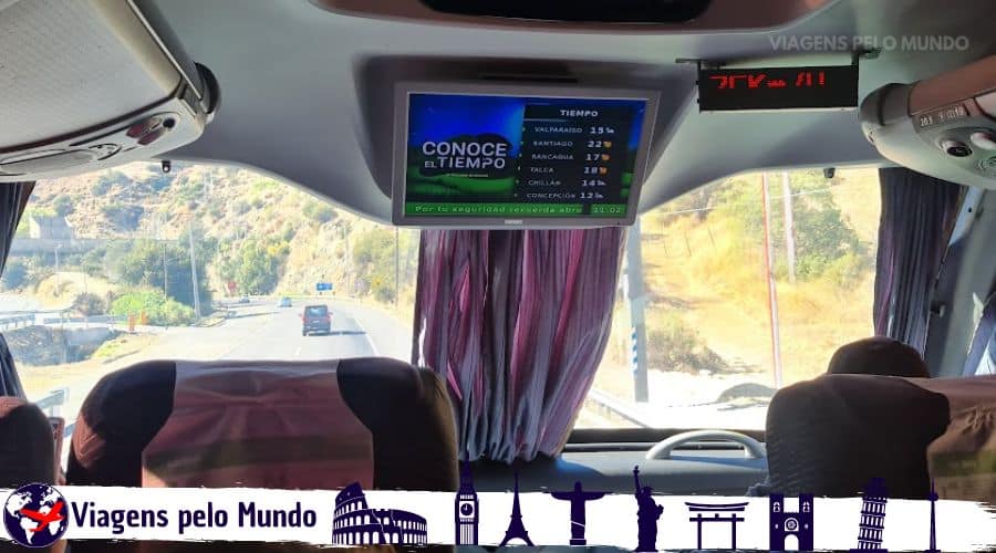 Ônibus que pegamos da Turbus. Interior de um ônibus com tela mostrando previsão do tempo durante a viagem de Santiago a Valparaíso.