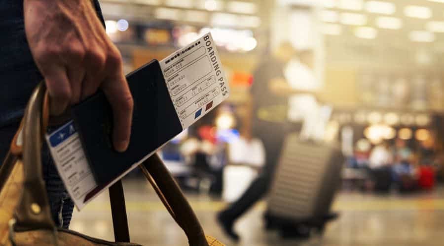 Pessoa segurando o passaporte e o cartão de embarque no aeroporto.