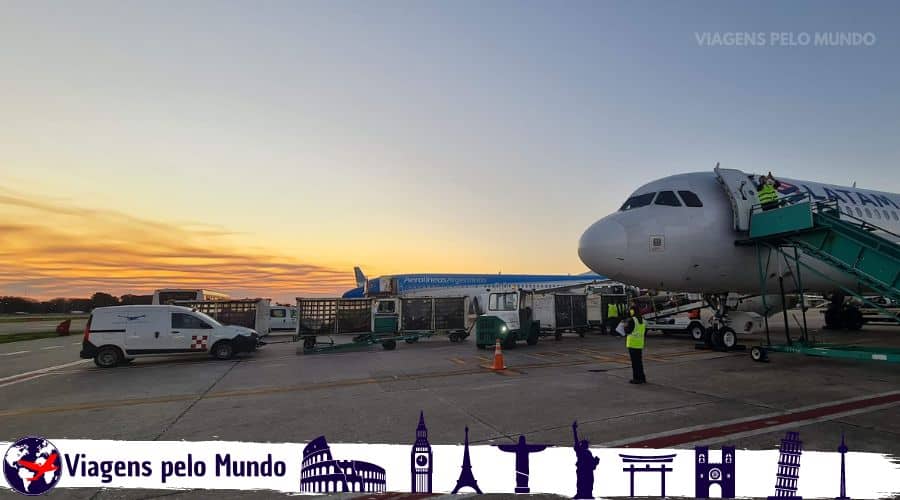 Pôr do Sol em Buenos Aires. Avião parada e equipe do aeroporto trabalhando no avião