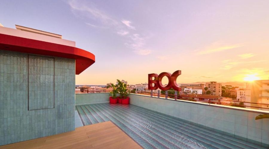 Terraço com uma piscina com o nome BOC e ao fundo o pôr do sol