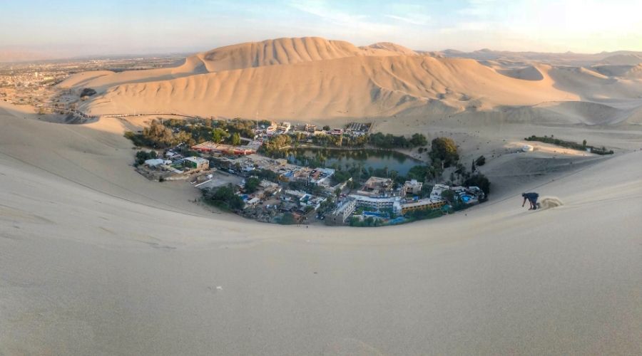 Dunas e no meio um lago com diversas construções, hotéis e restaurantes