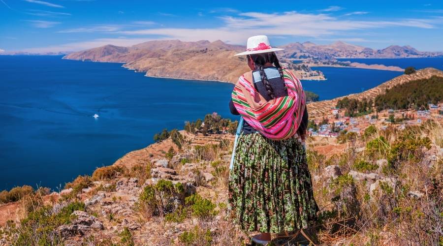 Mulher com roupa típica colombiana olhando para o Lago Titicaca
