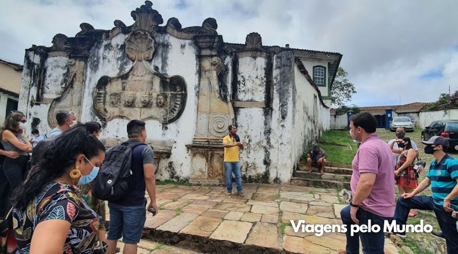 Guia na frente de uma fonte histórica em Ouro Preto